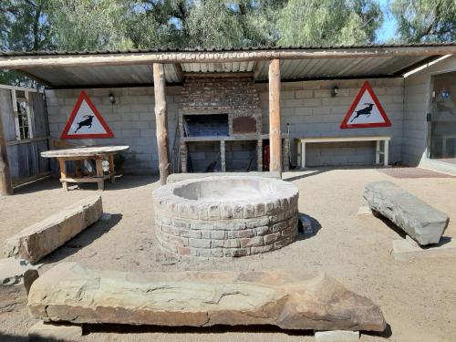 a building with a fire pit and two signs at Denmark Farm Stay in Cradock