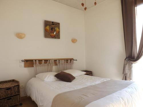 um quarto com uma cama com lençóis brancos e uma janela em Hôtel Le Carnon em Carnon-Plage