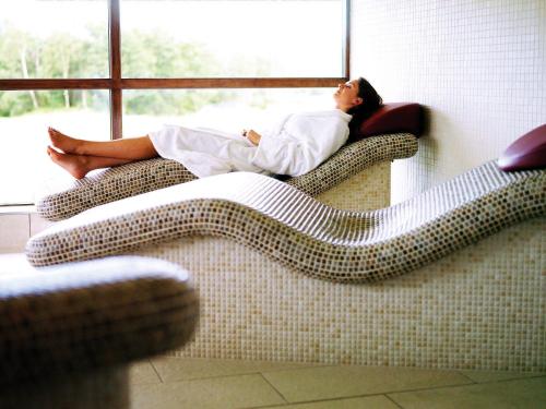 Una mujer tumbada en un sofá mirando por la ventana en CELEBRATE AT THE WORLD FAMOUS LOCH LOMOND RESORT CAMERON HOUSE - Sleeps 6, en Alexandria