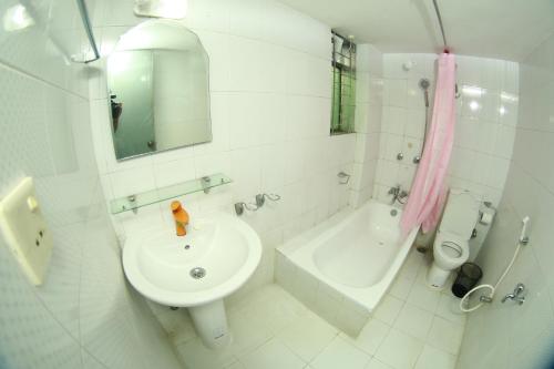 a white bathroom with a sink and a bath tub at Hotel Farmis Garden in Sylhet