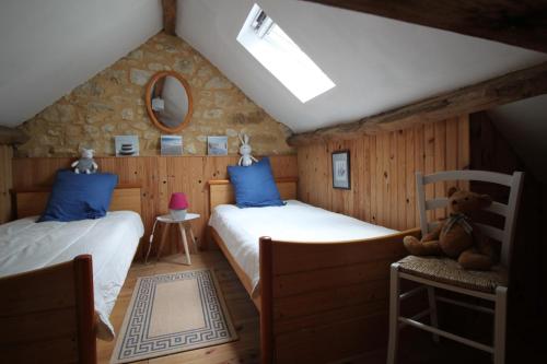 a bedroom with two beds and a teddy bear on a chair at La Maison de Lassagne in Saint-André-dʼAllas