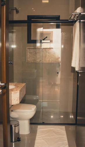 a bathroom with a toilet and a glass shower at OP'S HOTEL in Serranópolis