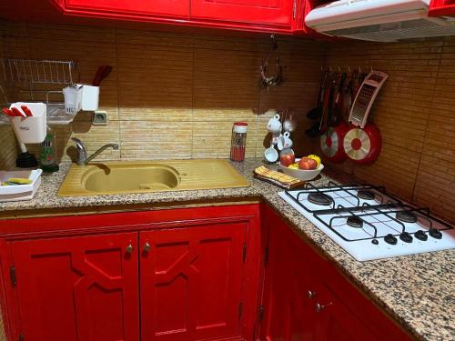 a kitchen with red cabinets and a sink and a stove at Très joli appartement au centre de IFRANE in Ifrane