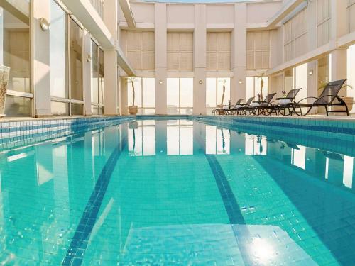 a large swimming pool with chairs in a building at Mercure Guarulhos Aeroporto in Guarulhos