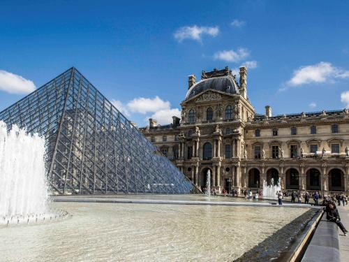 a glass pyramid in front of a building with a water fountain at ibis budget Porte D'Orleans in Paris