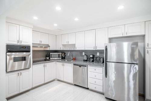 a kitchen with white cabinets and a stainless steel refrigerator at Sunny Isles Ocean Reserve Condo Apartments in Miami Beach
