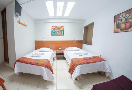 two beds in a room with a white wall at Inka's Rest Hostel in Puno