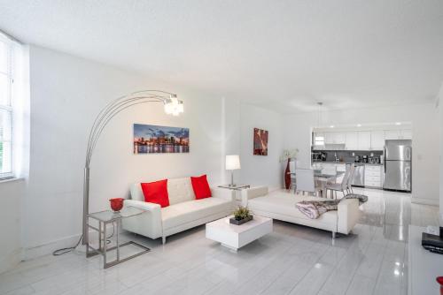 uma sala de estar com mobiliário branco e almofadas vermelhas em Sunny Isles Ocean Reserve Superb Condo Apartments em Miami Beach