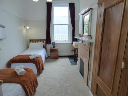 Habitación de hotel con 2 camas y ventana en Sahara Guest House, en Dunedin