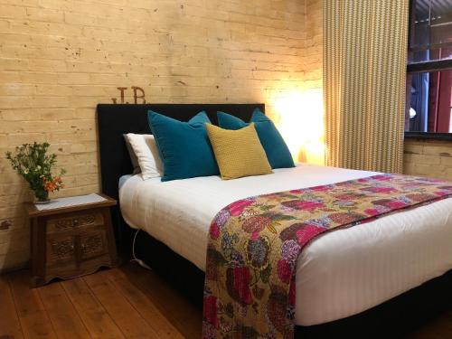 a bedroom with a large bed with blue and yellow pillows at The Shopkeepers Quarters in Tenterfield