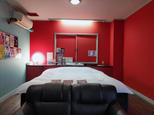 a red room with a bed and a couch at Hotel Room in Miyazaki