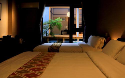 2 camas en una habitación de hotel con ventana en Hotel Traveling Bridge Nijojo, en Kioto