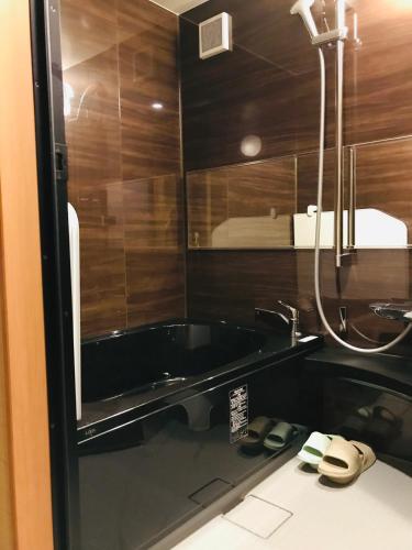 a bathroom with a bath tub and a sink at Hotel Traveling Bridge Nijojo in Kyoto