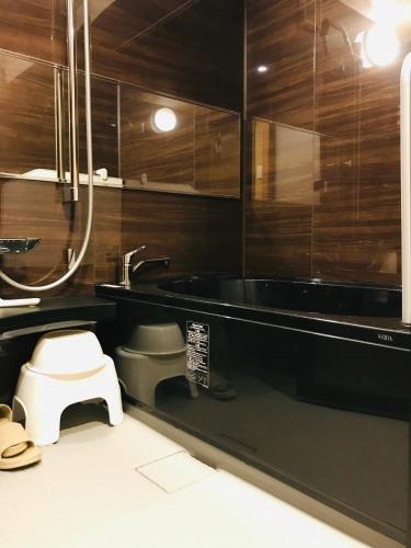 a bathroom with a tub and a toilet and a sink at Hotel Traveling Bridge Nijojo in Kyoto