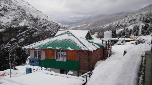 a house covered in snow next to a mountain at Himalayan High Trekkers Lodge - Sankri in Sankri