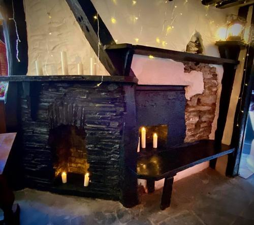 a stone fireplace with candles in a room at Jolly Sailor Inn in Looe