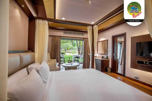 Un dormitorio con una gran cama blanca y una ventana en Avana Resort, en Mettuppālaiyam