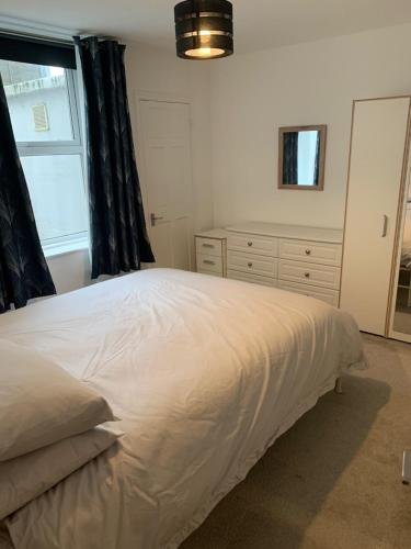 1 dormitorio con 1 cama blanca grande y ventana en Comfy flat in the heart of St Leonards, en St. Leonards