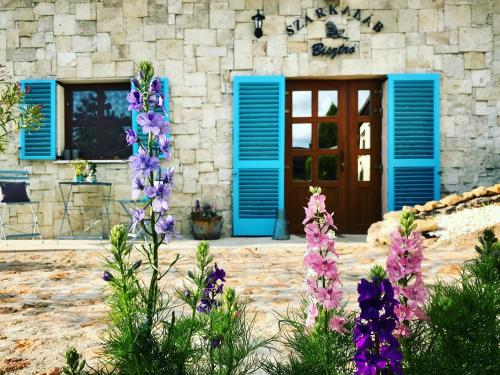 a building with blue shutters and purple flowers in front at Szarka Vendégház és Pince in Mád