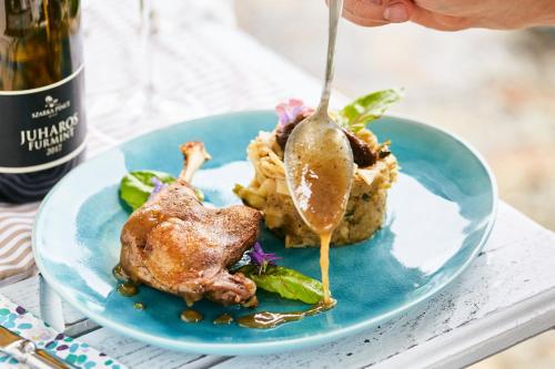 a blue plate with food on a table with a spoon at Szarka Vendégház és Pince in Mád