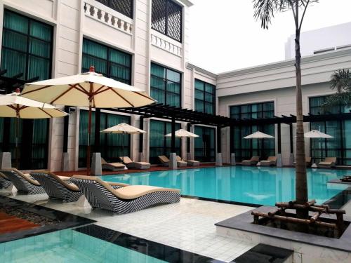 a hotel swimming pool with chairs and umbrellas at Mandarin Eastville, Pattaya - SHA Extra Plus in Pattaya North