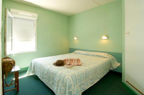 Fasthotel Lille Aéroport Lesquin في ليسكين: غرفة نوم خضراء مع سرير عليها قبعة