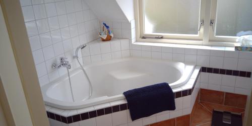 a bathroom with a bath tub with a blue towel at Ruime comfortabele villa Ouddorp in Ouddorp
