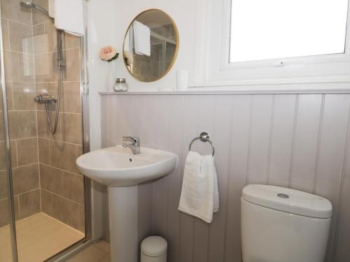 une salle de bain avec un lavabo, des toilettes et un miroir dans l'établissement Potter Hill Cottage, à Pickering