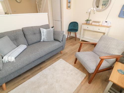 a living room with a gray couch and two chairs at Nana's House in Marazion