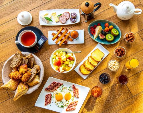 ein Holztisch mit Tellern mit Frühstücksspeisen und Getränken in der Unterkunft Chateau De Montreuil in Montreuil-sur-Mer