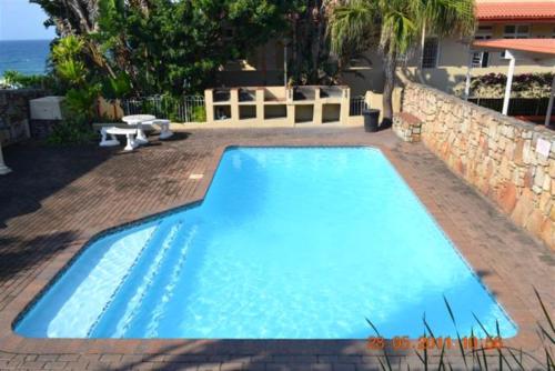 a large blue swimming pool next to a brick wall at Driftsands Sea View Flats in Uvongo Beach