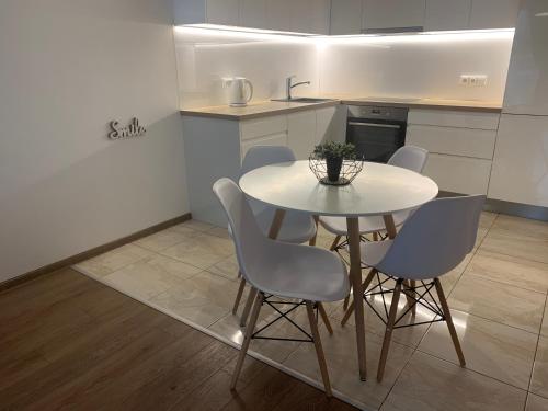 a kitchen with a white table and chairs in a room at Near Ozas in Vilnius