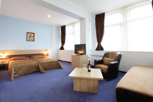 une chambre d'hôtel avec un lit et une chaise dans l'établissement Teodora Palace Hotel, à Ruse