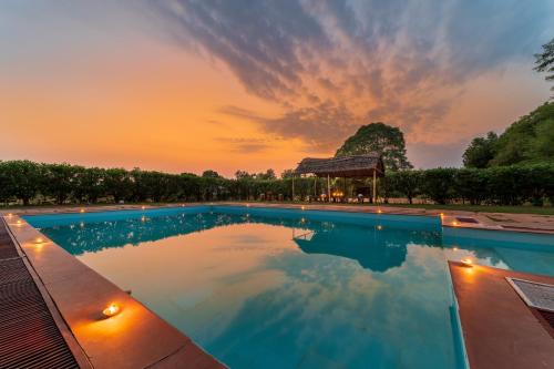 a swimming pool with a sunset in the background at Tiger Machan in Sawāi Mādhopur