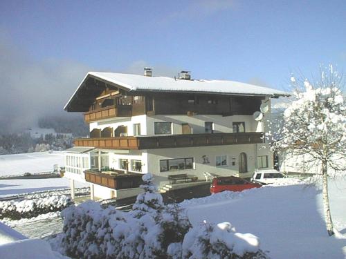 ein großes Haus im Schnee mit einem Auto davor in der Unterkunft Haus Hubertus in Mieders
