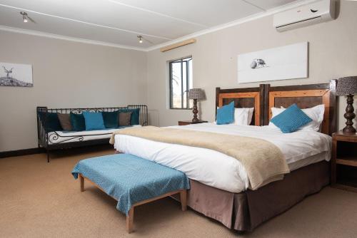 a large bedroom with a large bed and a bench at Tala Collection Game Reserve in Silverton