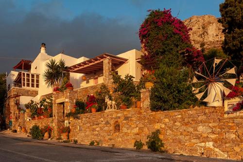 uma parede de pedra com uma casa e um moinho de vento em Pagali Hotel em Órmos Aiyialís