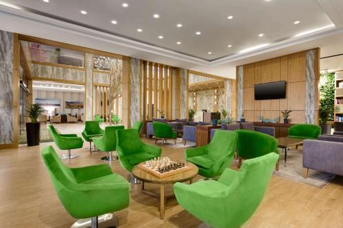 a hotel lobby with green chairs and a tv at Wyndham Garden Astana in Astana