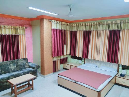 a bedroom with a bed and a couch at Hotel Ayodhya in Chiplun