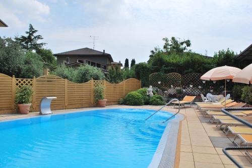a swimming pool in a backyard with a wooden fence at Hotel Alsazia in Sirmione