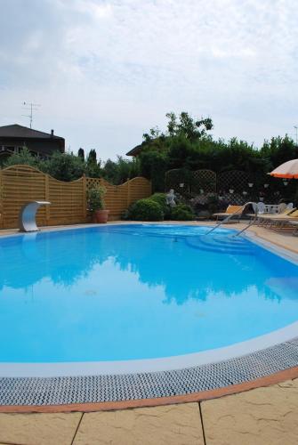 a large blue swimming pool in a yard at Hotel Alsazia in Sirmione