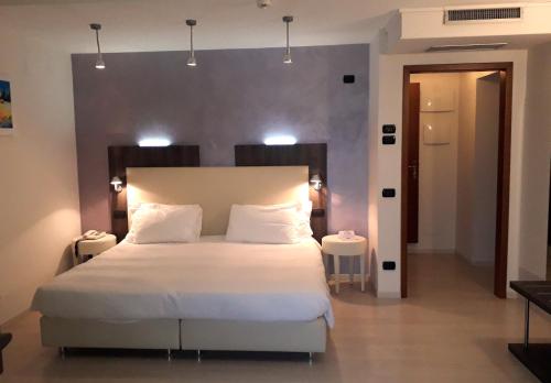 Un dormitorio con una gran cama blanca con luces encima. en Hotel L'Approdo en Pettenasco