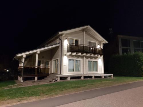 a white house with a balcony at night at Villa Saimaan Valo in Imatra