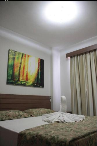 a bedroom with two beds and a painting on the wall at FLAT VEREDAS RIO QUENTE Apto 113 in Rio Quente