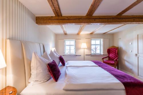 a bedroom with a large white bed with purple pillows at Magdalenengut Studios und Suiten in Erfurt