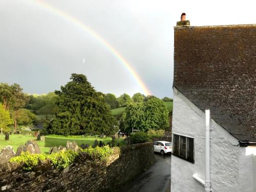 a rainbow in the sky over a house with a car at The Little House Harberton in Totnes