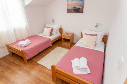 two beds in a small room with two tables at Villa Verbena in Mala Čista