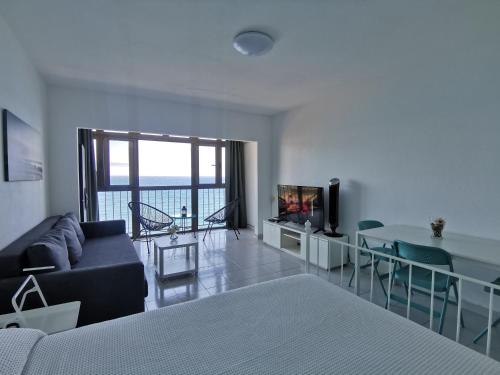 Una sala de estar con un sofá, una mesa y un televisor. en Mirador del Mar Sea Point Apartament, en Maspalomas