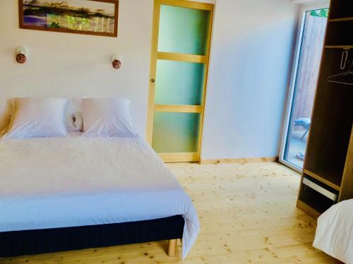 a bedroom with a white bed and a glass door at La Miellerie in Lannion