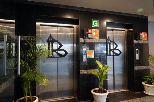 dos ascensores en un edificio con plantas delante de ellos en Hotel Bakya Slot - Maraimalai Nagar, en Chengalpattu